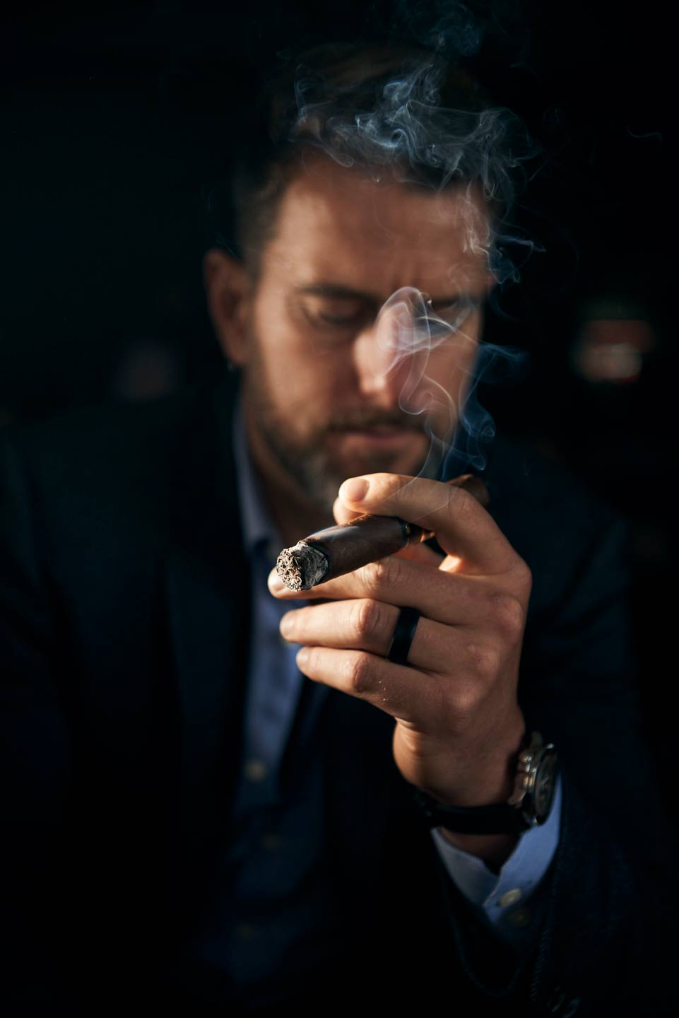 Moody lifestyle photography of man smoking cigar by Del Manning